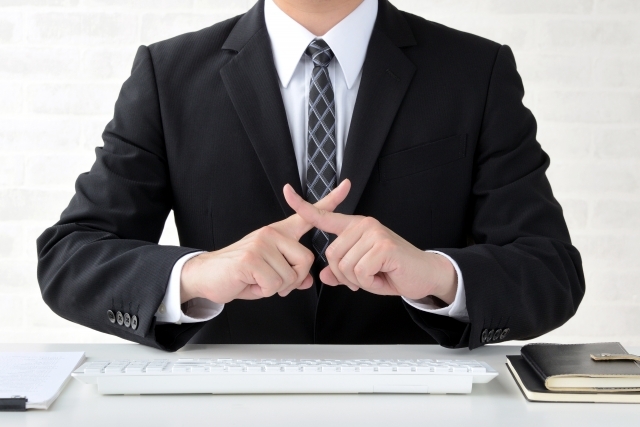 手でばつを作る男性