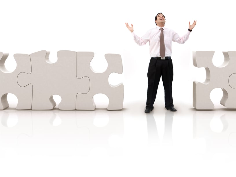Business man looking for the pieces of a puzzle- isolated over white