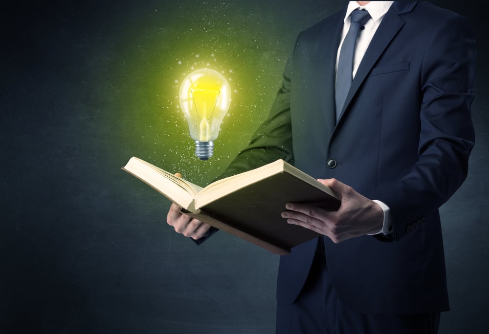 Businessman holding book with bulb.