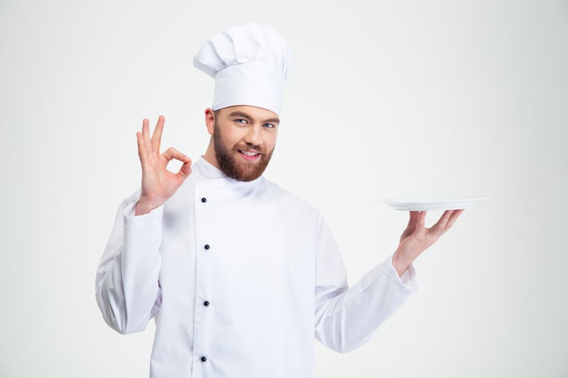 Portrait of a man chef showing ok sign and empty plate isolated on a white background