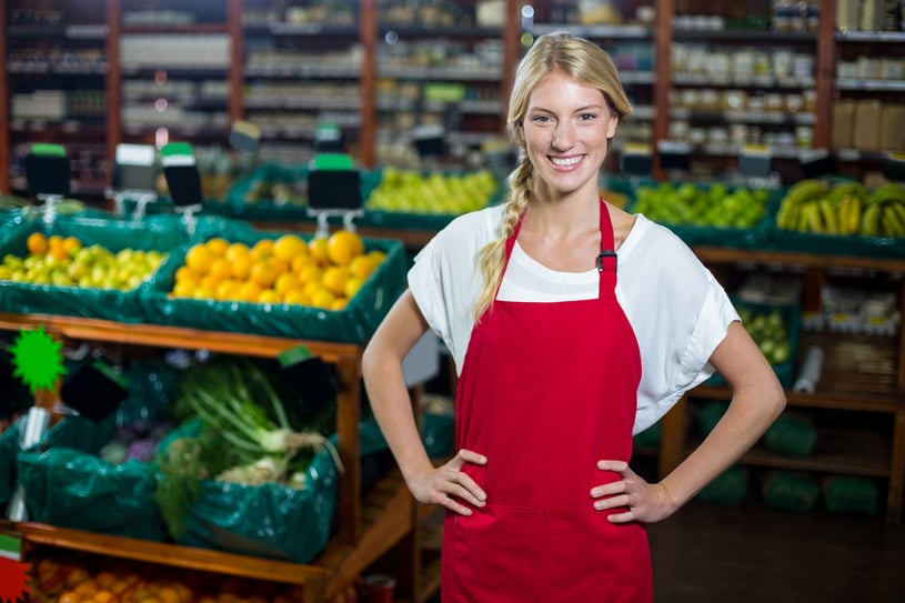 Portrait of smiling staff standing with hand on hip in organic section of supermarket
