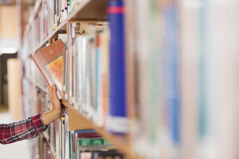 Pretty student taking book out of shelf in library