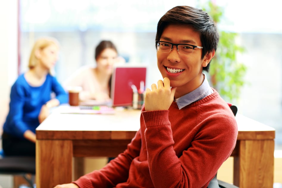 Young happy asian student sitting at the table